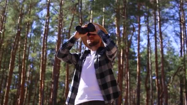 นักท่องเที่ยวชายมองผ่านกล้องส่องทางไกลในป่า องค์ประกอบการปีนเขา, ป่า . — วีดีโอสต็อก
