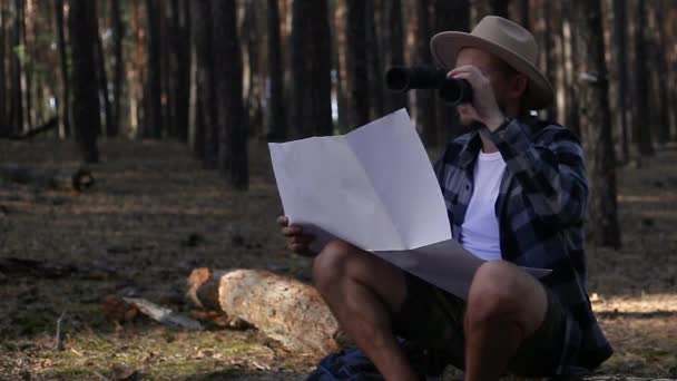 Young man resting, looking through binoculars and checking a map while hiking — Stock Footage Young man resting, looking through binoculars and checking a map while hiking Royalty Free Stock Footage