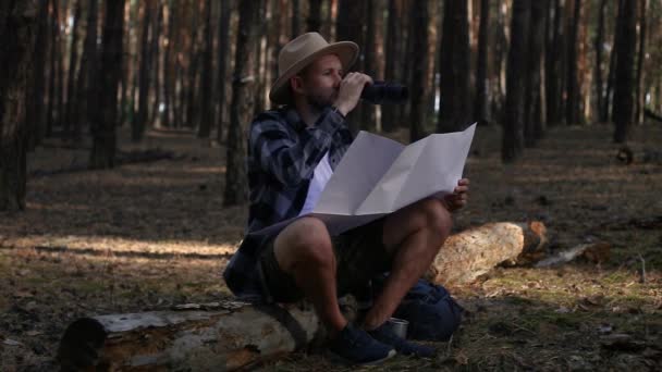 쉬고 있는 젊은 남자, 쌍안경을 통해 보고 하이킹을 하면서 지도를 확인하는 모습 — 비디오