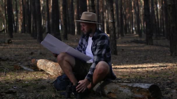 Joven descansando y revisando el mapa mientras camina por las montañas o el bosque — Vídeo de stock