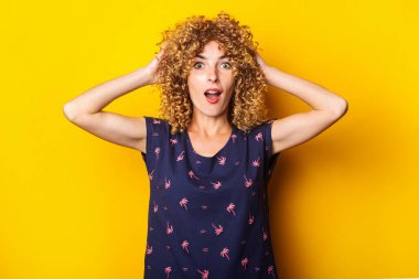 Şaşırdım. Güzel kıvırcık kadın ellerini sarı bir arka planda tutuyor.