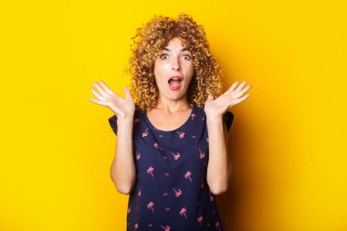 Şaşırdım, sarı arka planda güzel kıvırcık kadın.