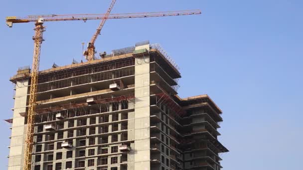 Edificio in costruzione e costruzione gru su sfondo cielo blu. — Video Stock