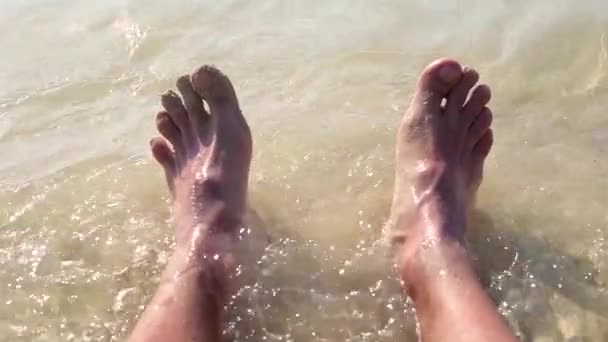 Surf de mer et pieds masculins sur la plage de sable. — Video