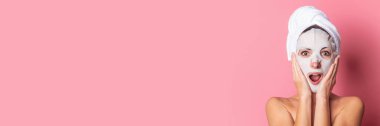 Pembe arka planda yüzü kozmetik maskeli genç bir kadın, spa tedavileri. Pankart