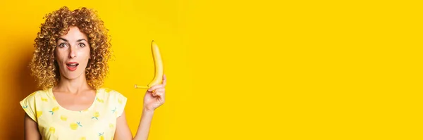 Shocked Surprised Curly Young Woman Holding Banana Yellow Background Banner — Stock Photo, Image