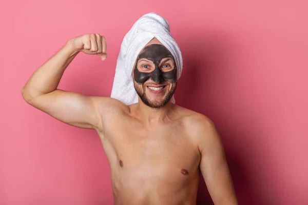 smiling man with a cosmetic mask on his face, naked shows muscles on a pink background.