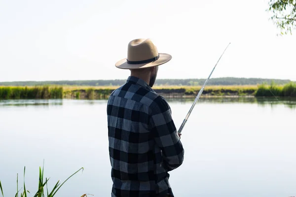 Şapkalı Ekose Gömlekli Bir Adam Nehir Kıyısında Balık Tutuyor — Stok fotoğraf
