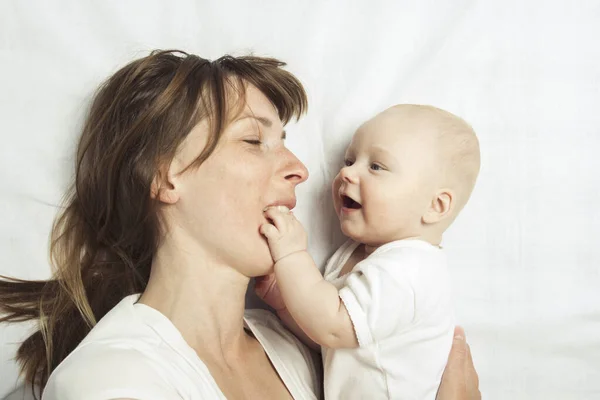 幼い母親は白いシーツのベッドで赤ん坊と遊ぶ フラットレイアウト トップビュー — ストック写真