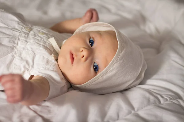 Маленькая Девочка Голубыми Глазами Белом Платье Кепкой Постели — стоковое фото
