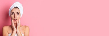Kafasında havlu olan genç bir kadın pembe arka planda yumuşak tene dokunuyor. Pankart