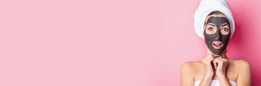 Pembe arka planda siyah maskeli, gözleri kapalı genç bir kadın. Pankart