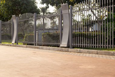 Yolun yanında uzun metal gri çitler var. Şehir çitlerinin sokağı.