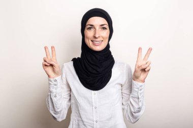 Beyaz gömlek ve tesettüre bürünmüş çapraz kollu genç bir kadın hoş bir jest sergiliyor. Pankart.