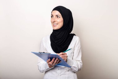 Beyaz gömlekli, tesettürlü ve tesettürlü dost canlısı bir Müslüman kadın. Pankart.