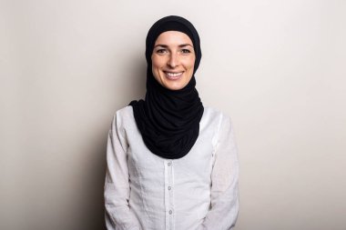 Beyaz gömlekli, tebessümlü ve tesettürlü genç bir kadın. .