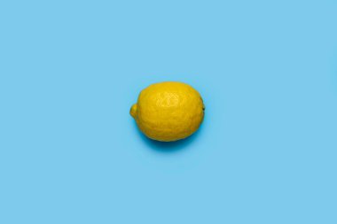 Mavi arka planda olgun sarı bir limon. Üst manzara, düz uzanma.
