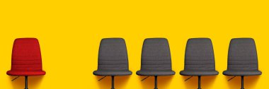 Bir kırmızı ofis sandalyesi ve sarı arka planda dört gri ofis sandalyesi. Pankart. 