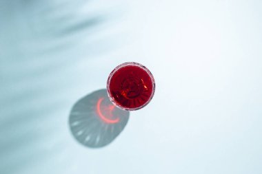 Mavi arka planda kırmızı şarap bardağı. Üst manzara, düz uzanma.