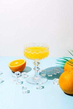 Portakal suyu, portakal suyu, buz küpleri, mavi arka planda palmiye yaprağı..