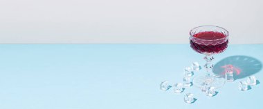 Kırmızı şarap bardağı, mavi zemin üzerinde buz küpleri. Pankart.
