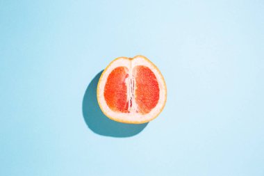 Mavi arka planda yarım bir greyfurt kes. Üst manzara, düz uzanma.