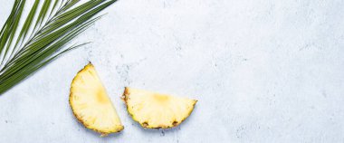 Beton zeminde ananas dilimleri ve palmiye yaprağı. Üst manzara, düz yatış. Pankart.