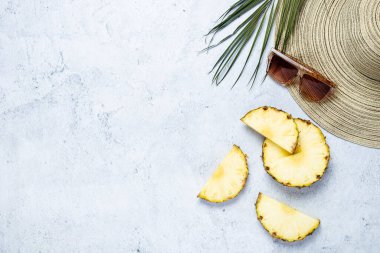 Kadın şapkası, güneş gözlüğü, ananas dilimleri, arka planda palmiye yaprağı. Üst manzara, düz uzanma.