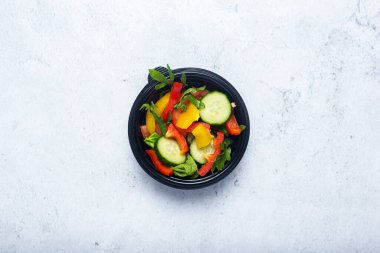 Beton bir arka planda plastik bir kasede sebze salatası. Üst manzara, düz uzanma. 