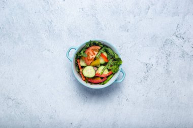 Beton arka planda mavi bir kasede sebze salatası. Üst manzara, düz uzanma.