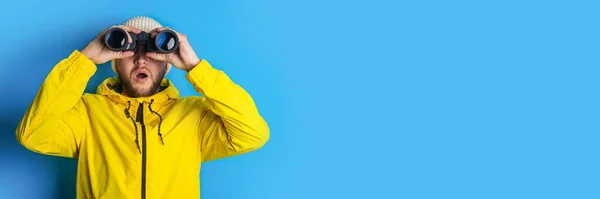 Sarı Ceketli Genç Adam Mavi Arka Planda Dürbünle Yan Tarafa — Stok fotoğraf
