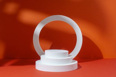 Kırmızı zemin üzerinde tropik yapraklar altında sunum için beyaz daire ve oval podyumlar. 