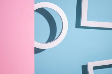 Mavi arka plandaki yuvarlak halka podyumu pembe karton arka plandan dışarı bakıyor. Üst manzara, düz uzanma. 