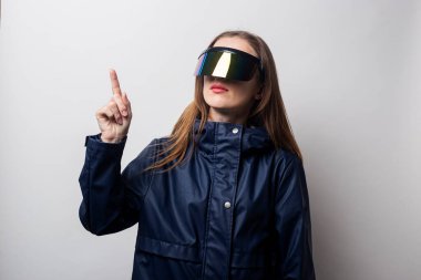 Sanal gerçeklik gözlüklü genç kadın arka planda bir başparmak gösteriyor..