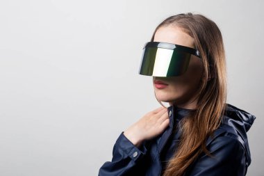 Sanal gerçeklik gözlüklü ve açık arkaplanda mavi ceketli bir kadın..