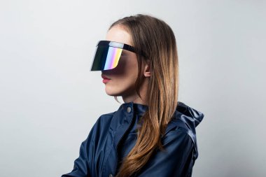 Sanal gerçeklik gözlükleriyle ve açık arkaplanda mavi ceketli genç bir kadın..