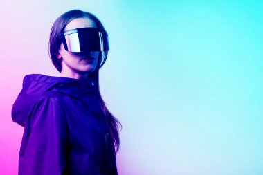 VR gözlüklü ve mavi ceketli genç bir kadın arka planda hafif bir eğim eklemiş.. 