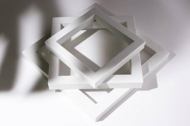 Beyaz kare podyumları beyaz zemin üzerinde tropik bir yaprağın gölgesi altında sunum için çerçeveler.