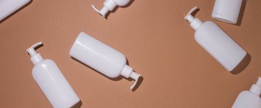 Dispanser şişeleri kahverengi karton arka planda yatar. Üst manzara, düz yatış. Pankart.