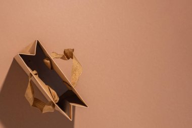 Kahverengi arka planda saten kurdeleli bir el işi hediye paketi. Üst manzara, düz uzanma.