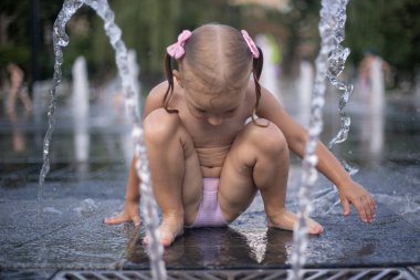Küçük bir kız çeşmenin derelerinin altında yıkanır..