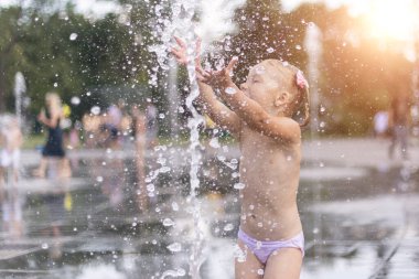 Sağlıklı bir kız çeşmenin derelerinin altında banyo yapar.