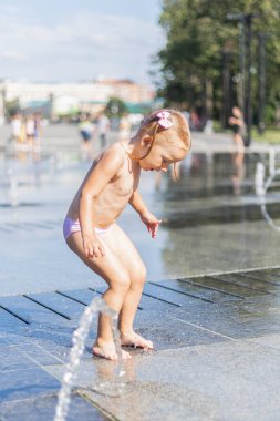 Küçük bir kız çeşmenin derelerinin altında yıkanır..