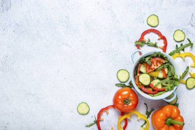 Sebze salatası pişirmek, arka planda mavi bir kasede sebzeler. Üst manzara, düz uzanma.