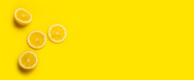 Sarı arka planda limon dilimleri ve dilimlenmiş limon. Üst manzara, düz yatış. Pankart.
