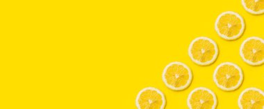 Sarı arka planda olgun limon dilimleri. Üst manzara, düz yatış. Pankart.