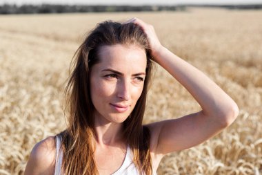 Genç kadın güneşli bir günde buğday tarlasında.