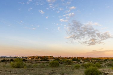 Portekiz 'in Algarve kentindeki Armao de Pra yakınlarında, ılık altın saat ışığıyla aydınlatılan kıyı sulak alanları ve çayırlar geniş bir görüş alanına sahiptir. Yumuşak bulutlar, mavi gökyüzü ve barışçıl bir doğal atmosferi vardır.