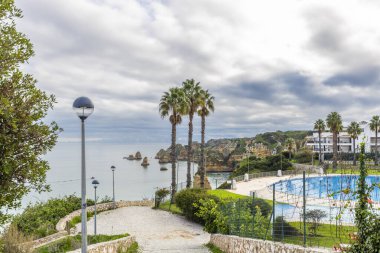 Lagos, Algarve, Portekiz 'deki sahra manzarası dramatik kireçtaşı uçurumları, sakin Atlantik suları ve denizden yükselen belirgin kaya oluşumları..