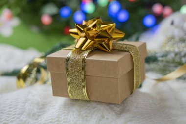 Hediye kutuları, yeni yıl ve sevgililer günü için arkaplanda süslü bir battaniyeye sarılı altın rengi kurdele ve kurdele ile paketlenir.